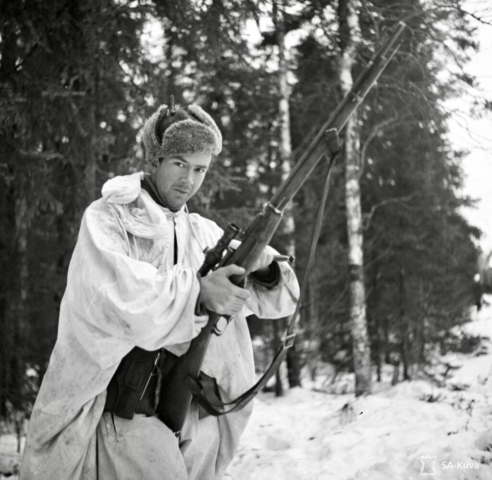 Finnish solider with a scoped, five-shot, bolt-action Mosin-Nagant rifle captured from Russian forces (the Finns had very few scoped rifles when the war started). The Russian-made Mosin-Nagant, which was produced from 1882 to 1891, is one of the most mass-produced military bolt-action rifles in history; more than 37 million units were made. It continues to be used in various conflicts around the world today. After the Winter War, the Finns tended to hold on to captured models such as this one for hunting. Photo credit SA-Kuva Finnish soldier with a M91/30 rifle, the Finnish version of the Russian-made Mosin-Nagant rifle. Much better than the Russian version, the M91/30 had excellent iron sights graded for 50-meter variations. Note the soldier’s hat cover, which also folded down over the face, completing the camouflage. Photo credit SA-Kuva