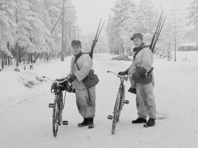 Bicycle troops—likely Swedish volunteers—carrying captured weapons. The Finns would patrol roads after Russian columns had passed through and collect anything of use. They captured vast amounts of materiel during the war— everything from rifles and radio sets to abandoned tanks. Photo credit SA-Kuva Bicycle troops—likely Swedish volunteers—carrying captured weapons. The Finns would patrol roads after Russian columns had passed through and collect anything of use. They captured vast amounts of materiel during the war— everything from rifles and radio sets to abandoned tanks. Photo credit SA-Kuva