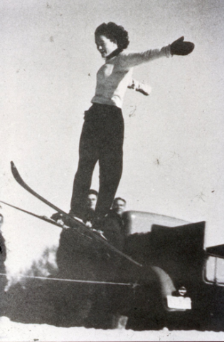 Rope tow at Woodstock, New Hampshire. When rope tows first began, “people had more fun going up than coming down” because the tow operators (in this case, sitting on the hood of the truck) would speed the tows up, which could wreak havoc with passengers such as the one depicted here. Photo credit: New England Ski Museum